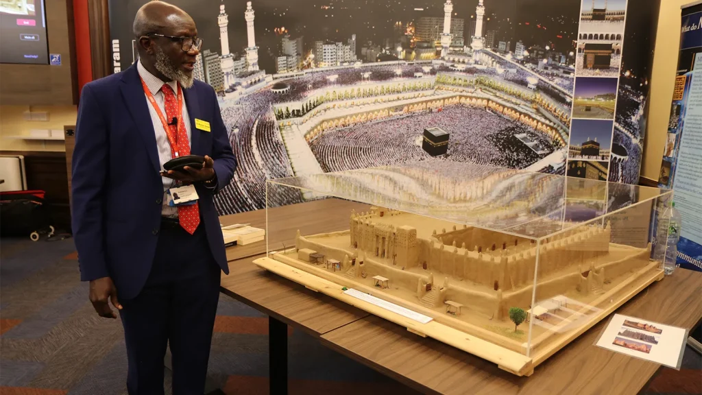 Scale model of the Great Mosque of Djenné in a clear case with a guide beside it