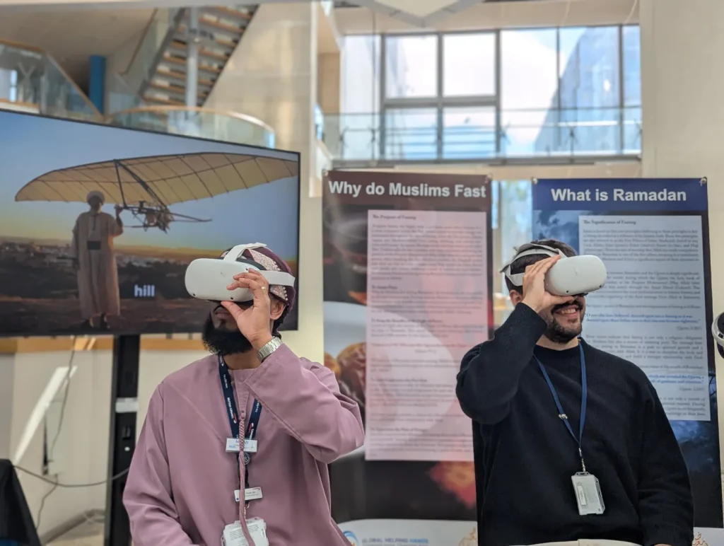 Two visitors wearing VR headsets in front of panels about Ramadan